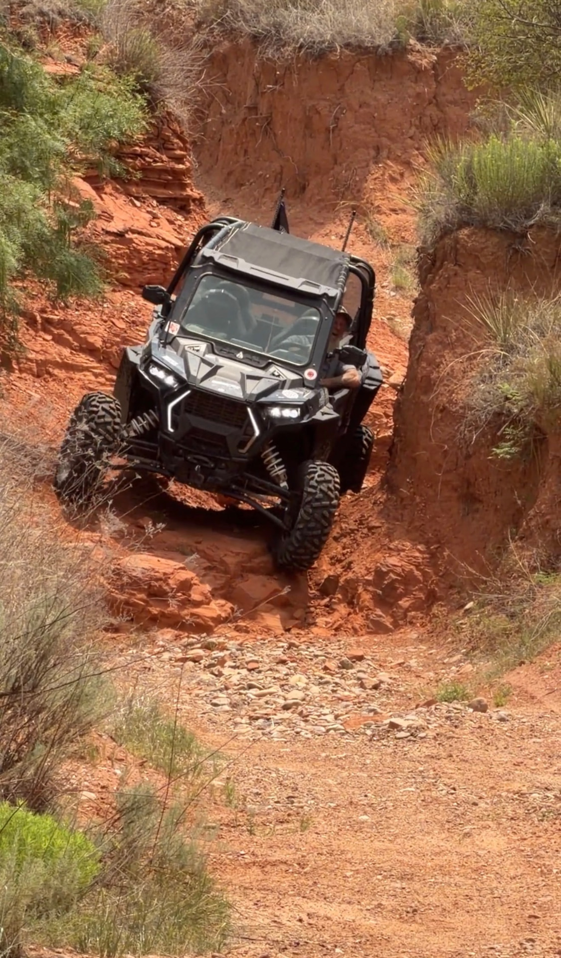 Polaris RZR side-by-side descending a red-rock Canadian River canyon trail
